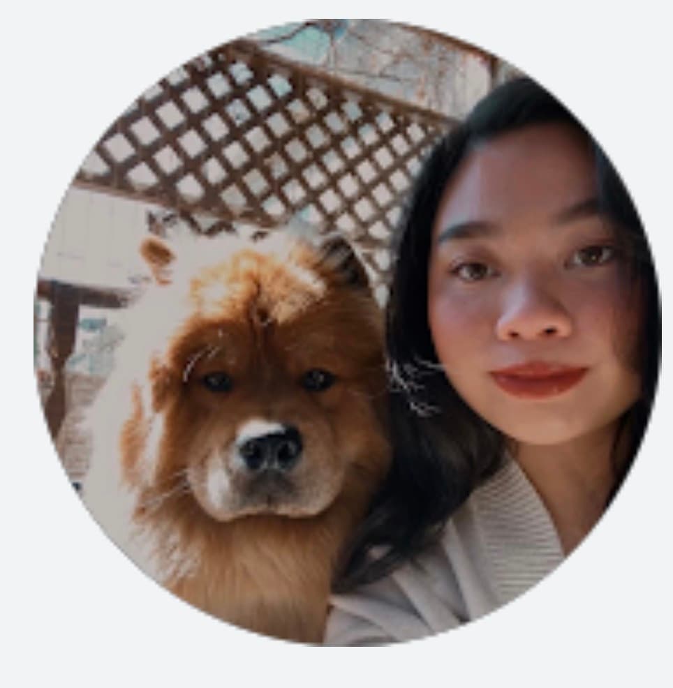 Young woman with dark hair posing with a fluffy brown dog under a lattice.